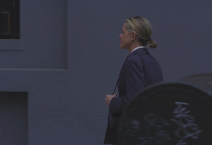 Woman in blazer walking on a city sidewalk
