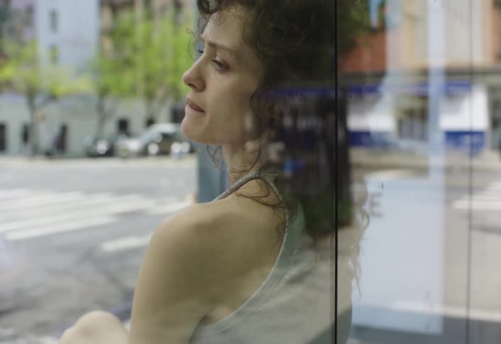 Curly haired woman sitting at a bus stop in the city