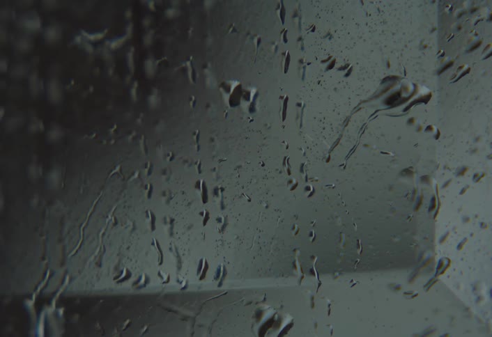 A persons finger passing over the surface of a mirror that is wet and he is removing some drops
