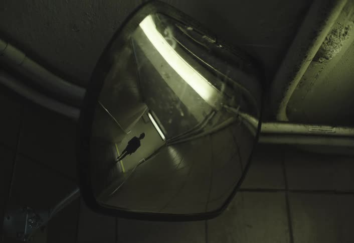 Person descending the stairs of a terminal seen through a mirror on the ceiling