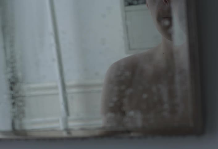 Shirtless person looking at himself in bathroom mirror