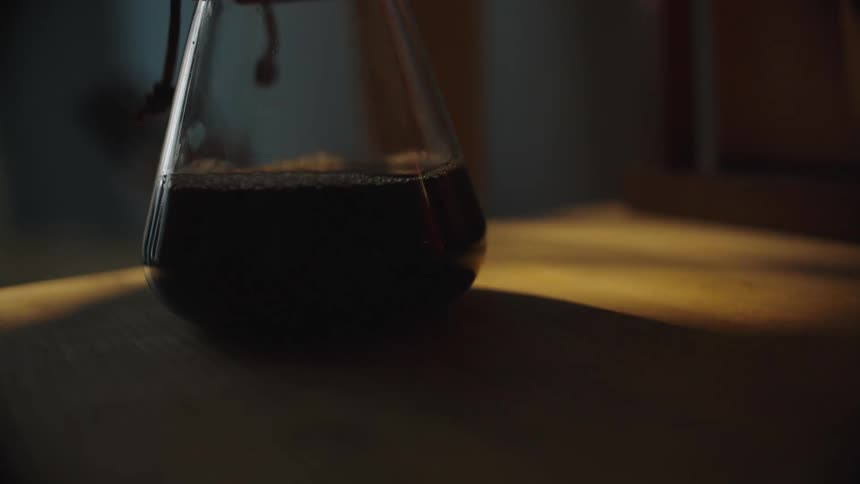 Drop falls to the bottom of a glass container while coffee is brewed