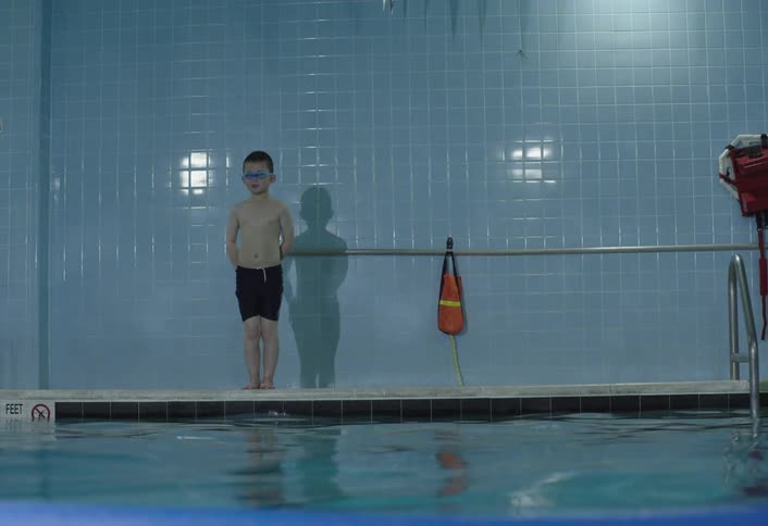 Boy dives into a swimming pool and swims across