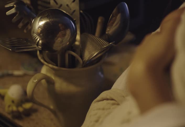 Mother holding a baby on her lap reflected in a metal spoon in a vase