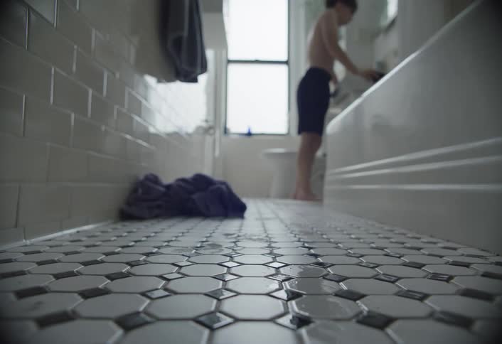 Boy walking through bathroom and heading towards sink with mirror