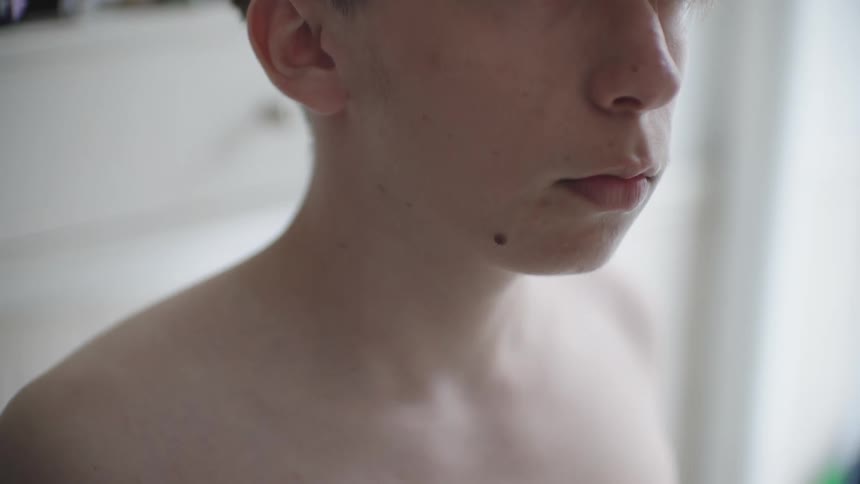 A teenager removes his shirt in the bathroom