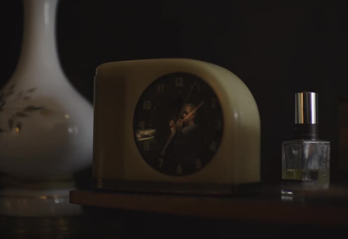 A man is reflected in the glass of the clock