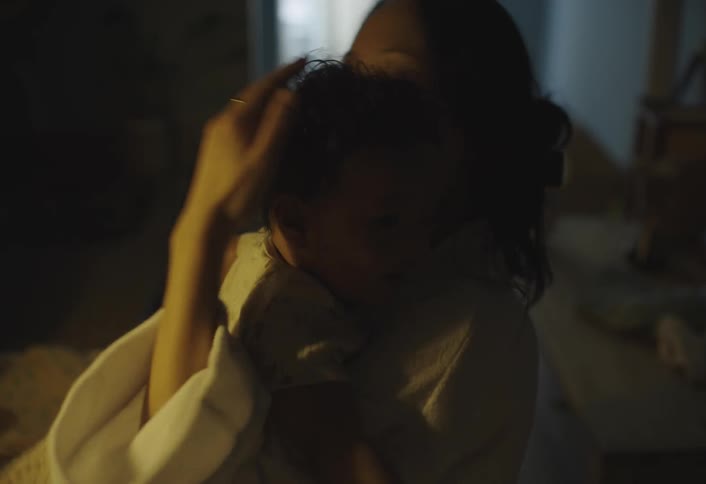 Mother gently cradles her infant in her arms soothing the baby to sleep