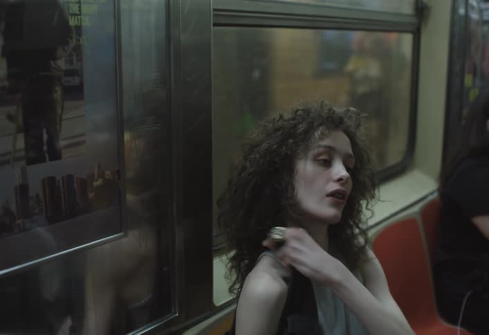 A woman sitting on a bus gets up and walks when the bus stops