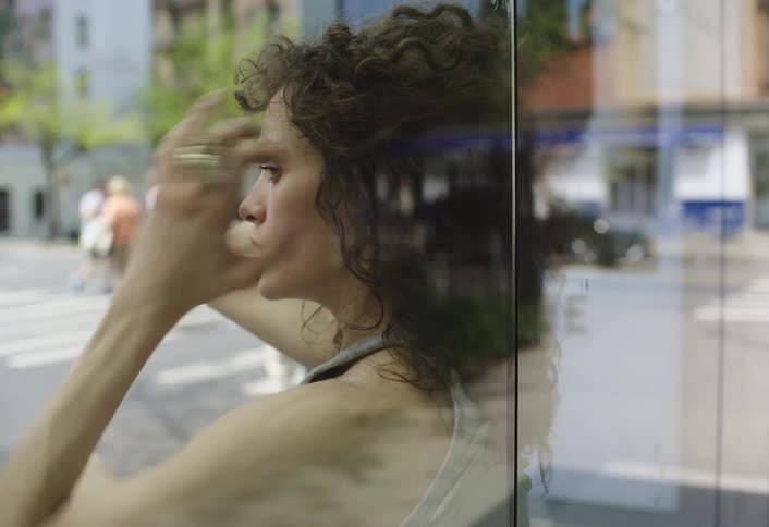 Woman putting her hands in her hair while sitting at a bus stop