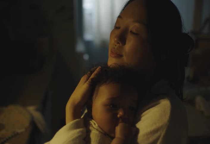 A mother holds her child over her shoulder soothing the baby gently