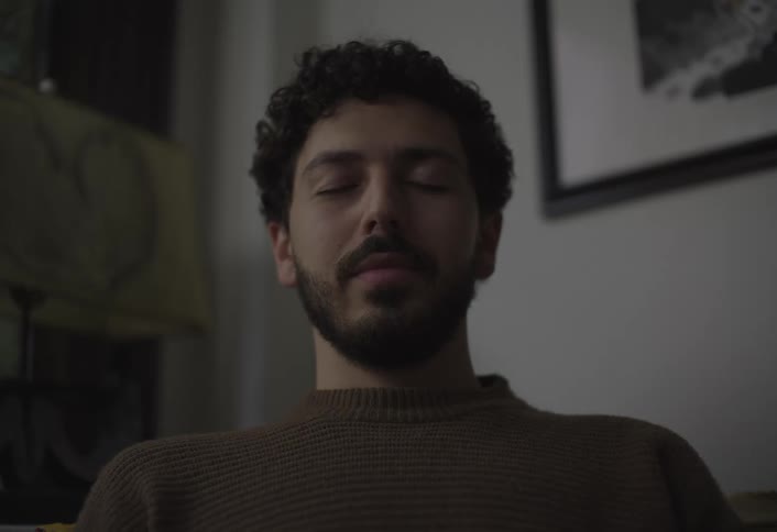 Young person breathes calmly smiles at camera while meditating