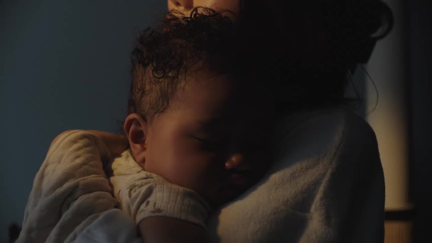 A peacefully sleeping infant rests in their mothers arms