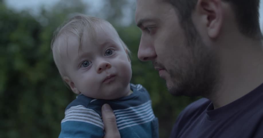 A father is holding his baby outside