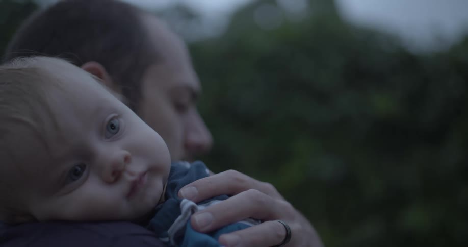 The baby is resting on his fathers shoulder