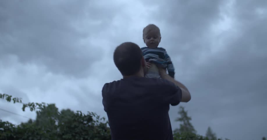 Father spinning with his baby son in his hands outdoors