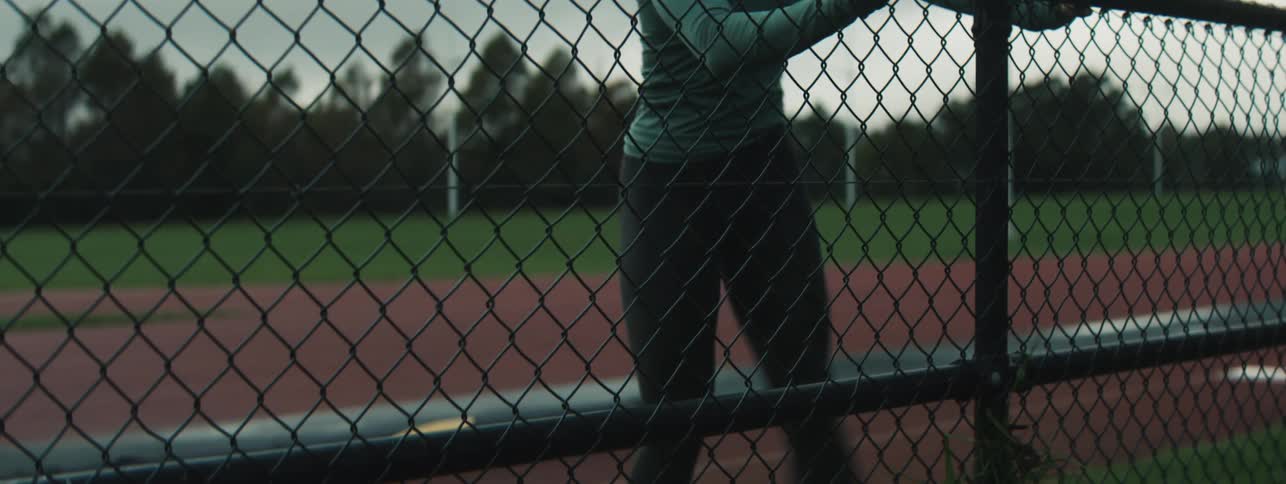 Woman stretching her leg on a metal fence