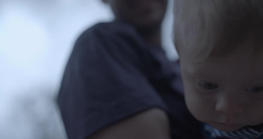A man holding a baby in his arms both looking down