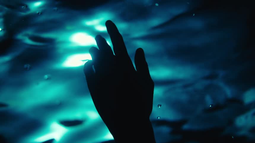 A person dips their hand in the dark water