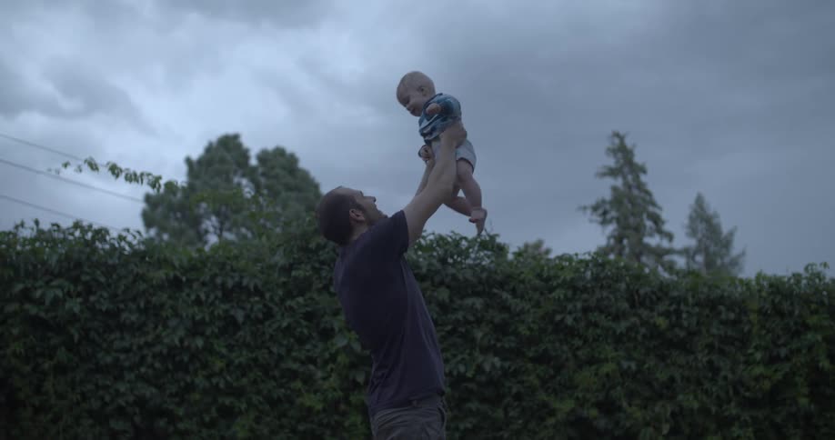 A father is raising his son in the air and spinning
