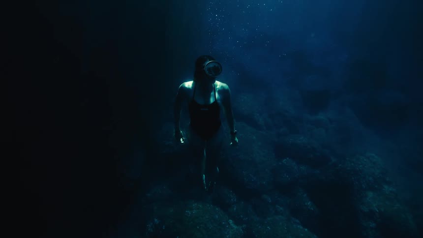 A woman swimming underwater rising toward the surface