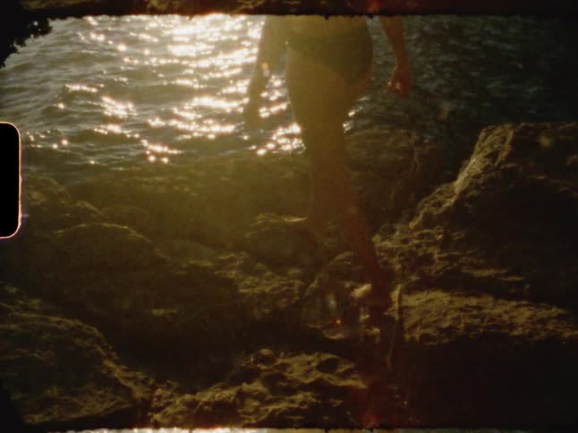 A woman climbs on the rocks of the shore