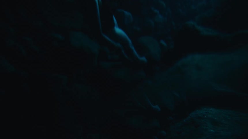 A woman standing on rocks at the bottom of the sea