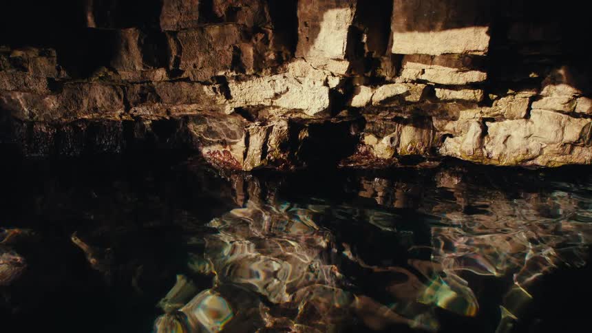 Crystal clear water with sun reflection in a cave