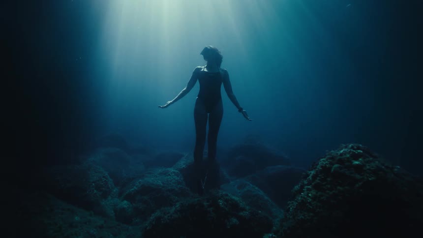Woman on rocks at the bottom of the ocean