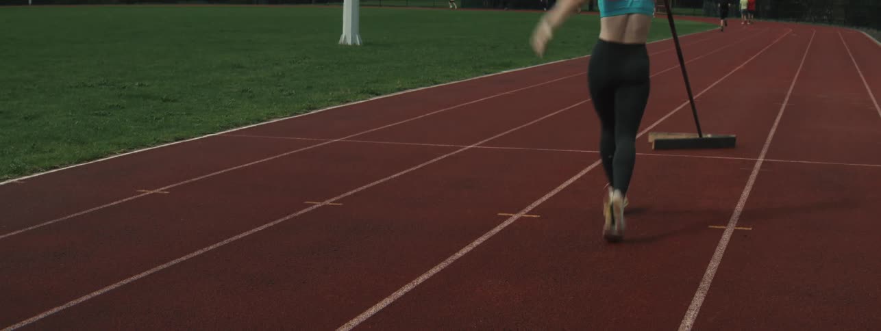 Woman with a stick playing sport on a running track