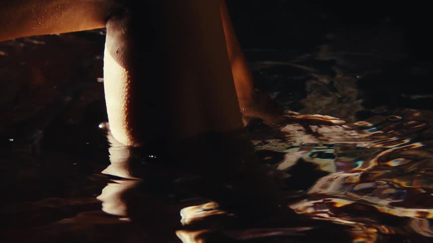Feet of a woman being placed in crystal clear waters