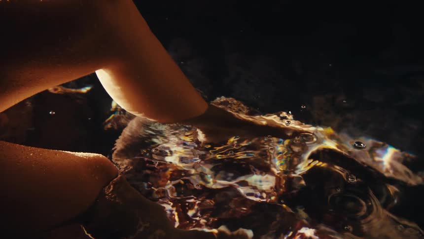 Womans legs entering crystal clear waters
