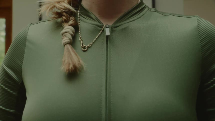 Woman putting on a green jacket and zipping up her cycling jacket