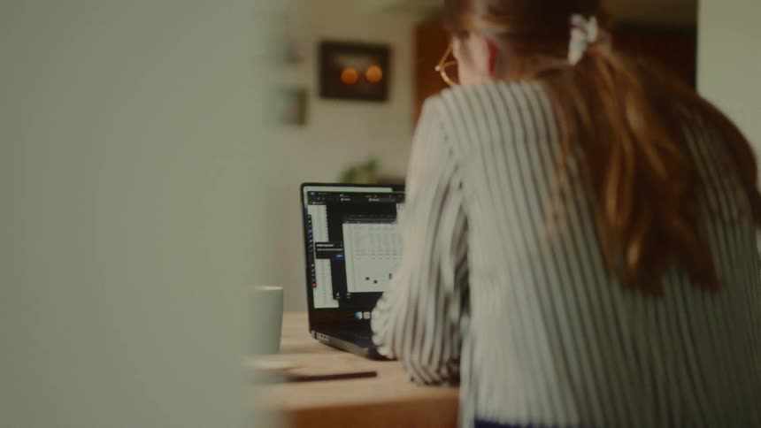 The woman is talking while looking at her laptop