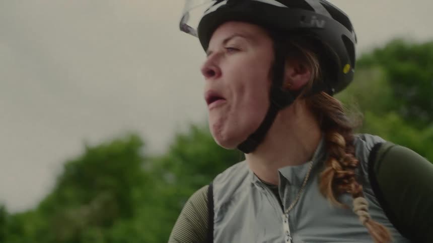 Woman in cycling clothes outdoors eating chewing with mouth