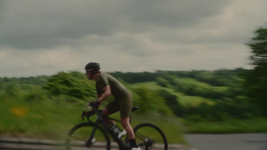 Cyclist riding up a road in a curve in an environment surrounded by vegetation