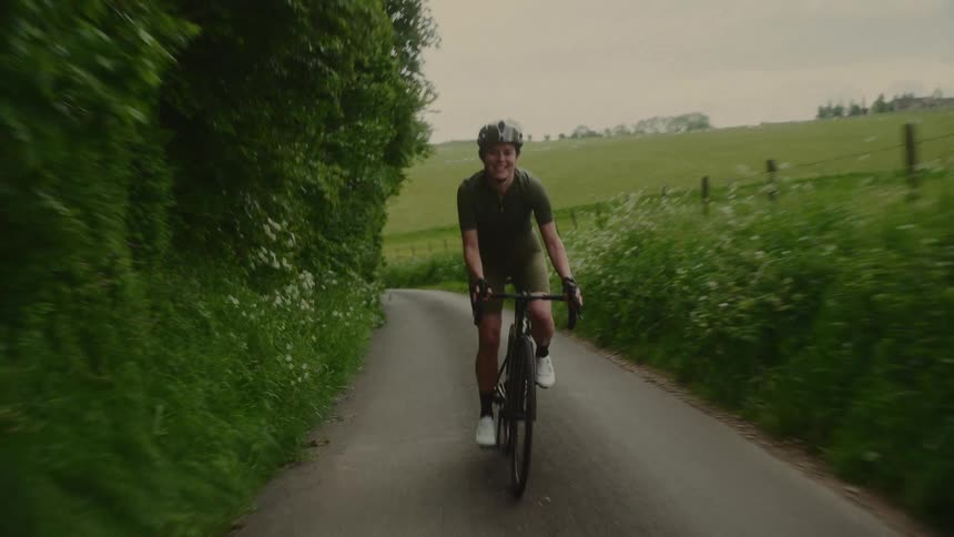 Woman wearing a helmet cycling through a rural setting