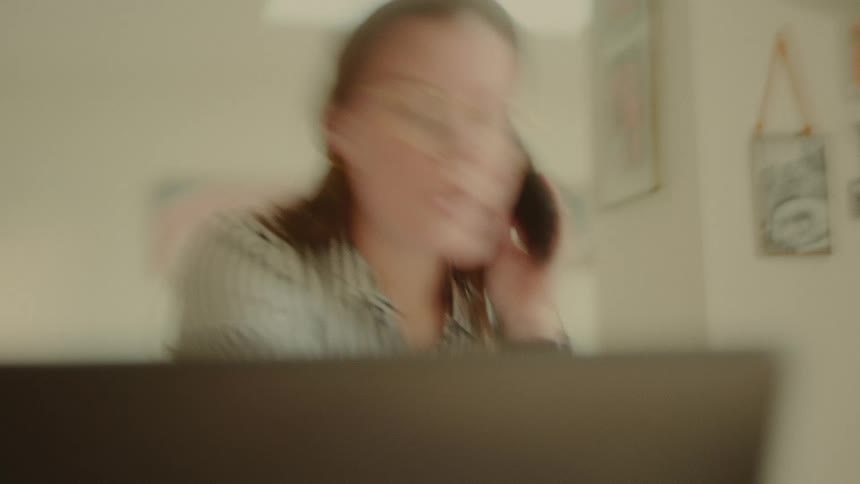 A woman is waving a pen while talking on the phone
