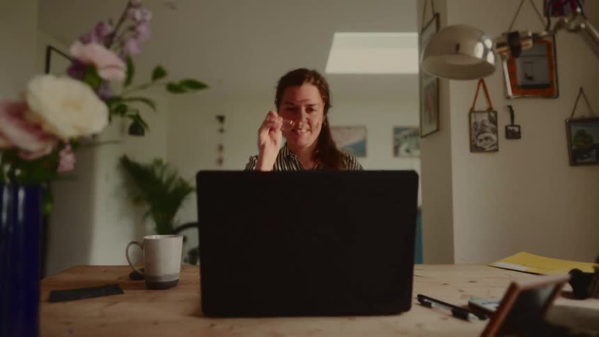 A woman smiles while opening her laptop