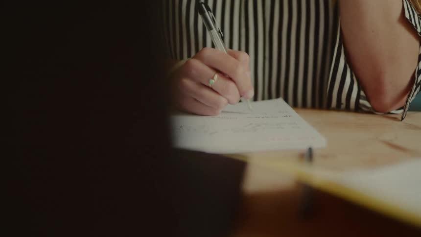 A woman is writing on a pad with a pen