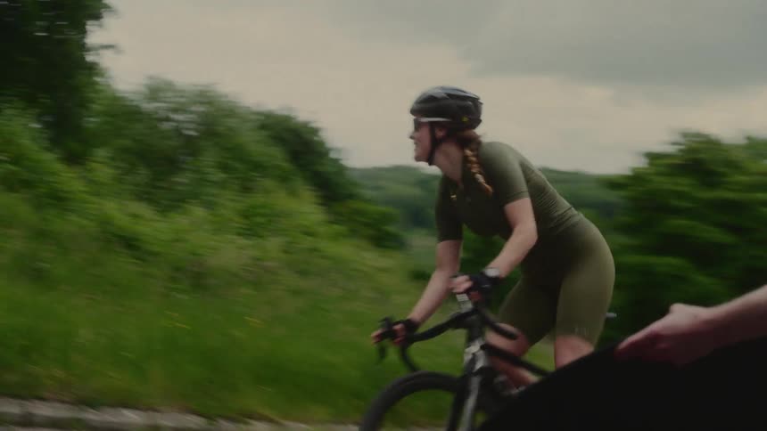 A person runs up to a biker rounding a curve