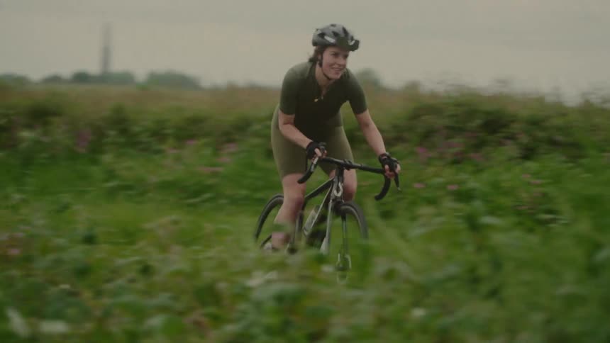 Female cyclist riding along a trail surrounded by green fields