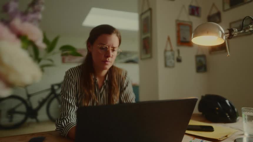 The woman is thinking as she types on the laptop