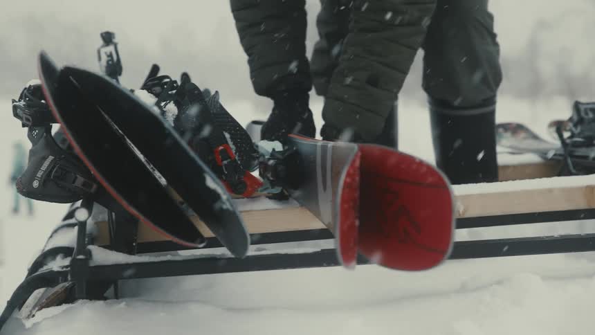 A person unloads snowboards in a snowy outdoor setting