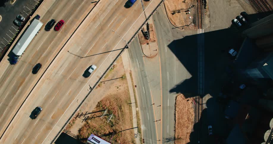 An aerial view of a bridge with many vehicles in motion and a paved road