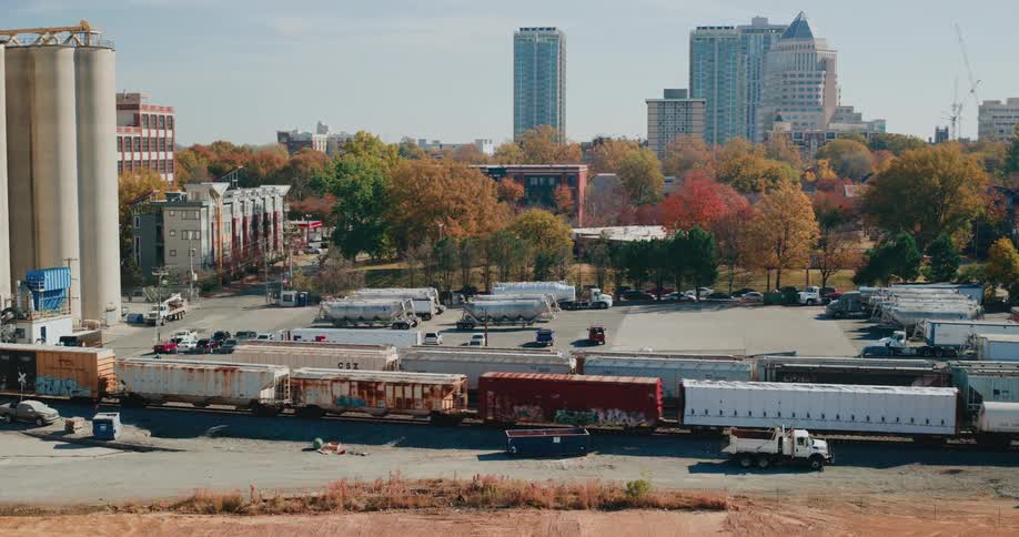 Freight trains rest on tracks near a treelined urban neighborhood