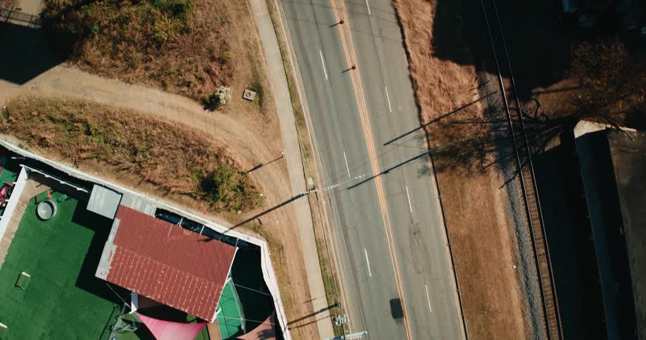 An aerial view of a paved road and a bridge with cars moving across the bridge