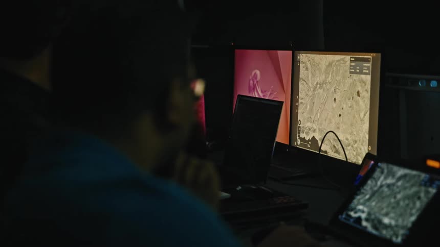 Two men are looking at maps on the computer screens