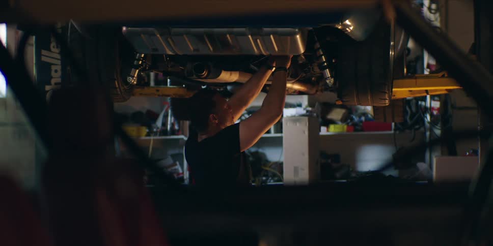 Mechanic under a car working on it
