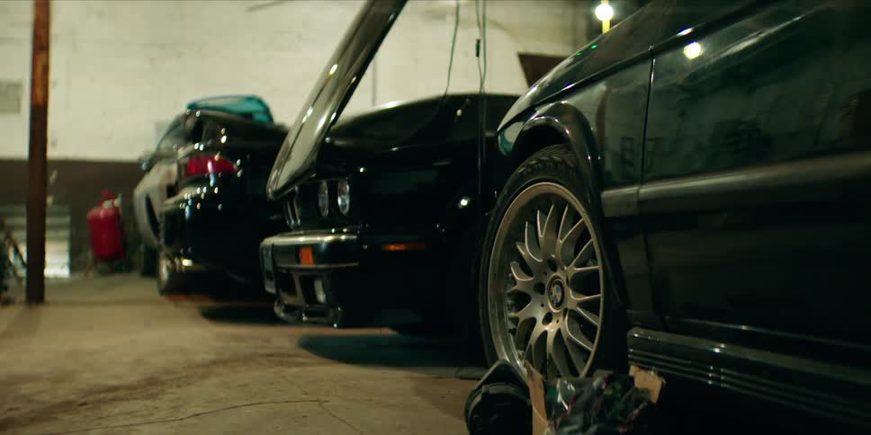 Several cars are parked closely inside a garage or auto repair workshop